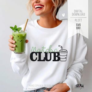 Könnte beinhalten: Weißes Sweatshirt mit den Worten "Matcha CLUB" in Schwarz und Grün. Das Design beinhaltet ein Matcha-Getränk in einem To-Go-Becher. Ein hohes Glas grünen Matcha-Tees mit Minze und Strohhalm wird in der Hand gehalten.