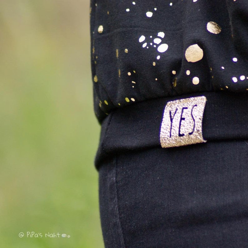 K&ouml;nnte beinhalten: Schwarzes Shirt mit goldenen Glitzer und einem silbernen Patch mit der Aufschrift "YES".