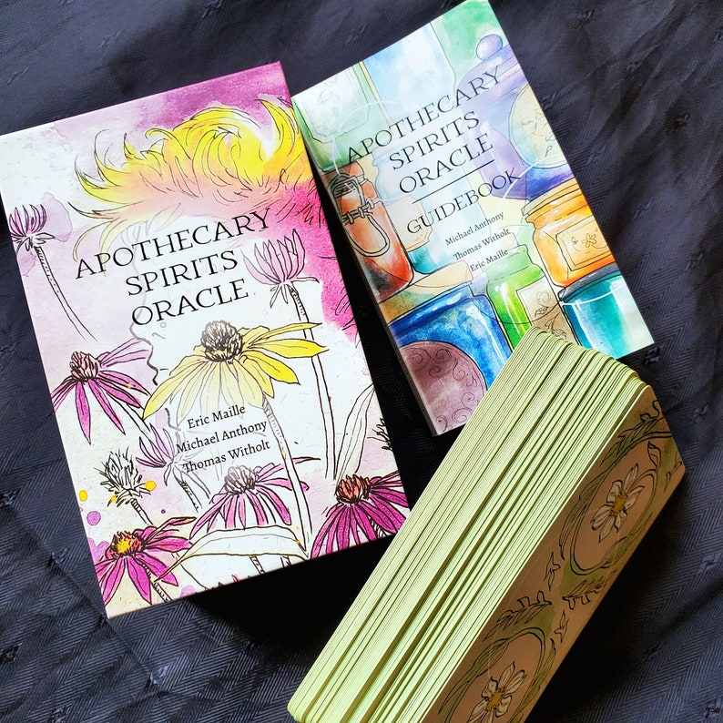 K&ouml;nnte beinhalten: Ein Deck Apothecary Spirits Oracle-Karten mit einem Handbuch. Die Karten zeigen ein gr&uuml;nes und goldenes Design mit einem floralen Motiv. Das Handbuch hat eine Aquarell-Illustration von Gl&auml;sern und Flaschen mit einem floralen Motiv.