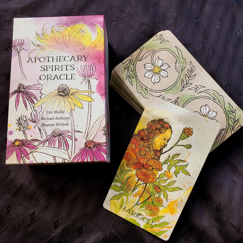 K&ouml;nnte beinhalten: Eine Schachtel mit Apothecary Spirits Oracle-Karten mit einer Aquarell-Illustration von Blumen auf der Vorderseite. Die Schachtel ist mit dem Titel "Apothecary Spirits Oracle" und den Namen der Sch&ouml;pfer beschriftet: Eric Maille, Michael Anthony und Thomas Witholt. Eine einzelne Karte aus dem Deck wird gezeigt, mit einer Aquarell-Illustration einer Ringelblume und dem Gesicht einer Frau.
