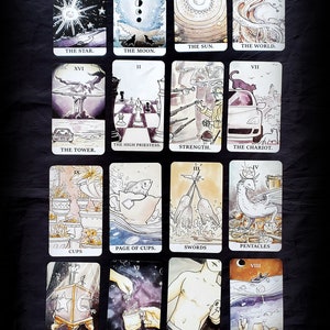 Pu&ograve; includere: Un set di 22 carte dei tarocchi con illustrazioni ad acquerello. Le carte presentano una variet&agrave; di immagini, tra cui animali, persone e oggetti. Le carte sono disposte in una griglia, con ogni carta che ha un numero e un titolo.