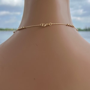 Puede incluir: Un collar de cadena de oro con un delicado dise&ntilde;o de cuentas. La cadena se muestra en el cuello de un maniqu&iacute;.
