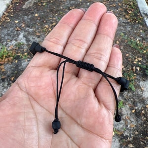 May include: A black adjustable bracelet with black cord and black bead accents.