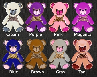 Peut inclure: Dix épingles en émail représentant des ours en peluche de différentes couleurs, notamment crème, violet, rose, magenta, bleu, marron, gris et beige. Chaque ours porte une corde dorée autour du cou.