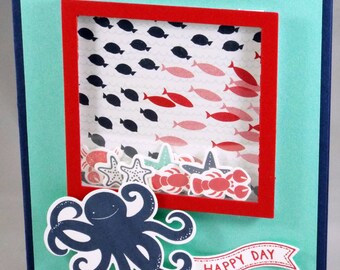 Tarjeta agitadora de vida marina hecha a mano con pulpo, pez, estrella de mar, langosta, cangrejo, feliz cumpleaños, bebé, felicitaciones, azul marino, aguamarina y rojo.