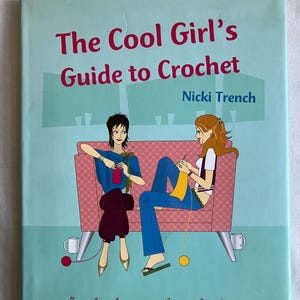 May include: A book titled "The Cool Girl's Guide to Crochet" by Nicki Trench. The cover features an illustration of two women crocheting on a pink couch. The book is light blue with red and black text. The text at the bottom reads "Everything the novice crocheter needs to know."