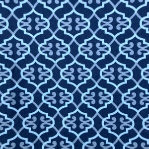 May include: A navy blue fabric with a repeating geometric pattern in light blue and gray. The pattern consists of interlocking quatrefoil shapes, creating a textured, decorative design. The fabric has a soft, matte finish.