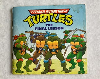 Puede incluir: Un cómic vintage de las Tortugas Ninja titulado "The Final Lesson". La portada presenta a las cuatro tortugas, cada una con una máscara de diferente color, sosteniendo armas. El fondo es azul claro con el título en amarillo y rojo.