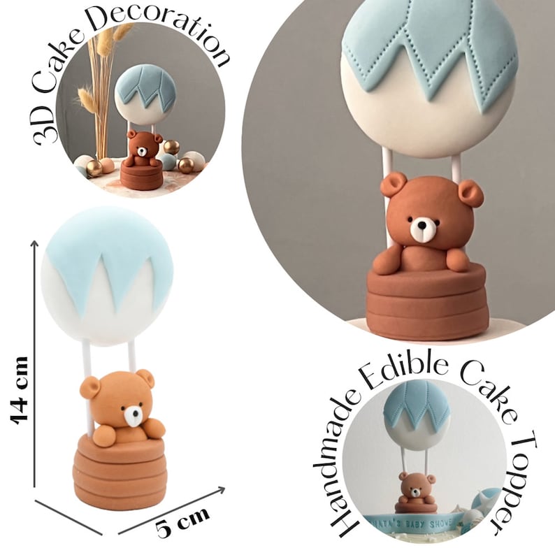 Fondant cake topper shaped like a brown teddy bear sitting in a round basket, attached to a white and light blue hot air balloon. The topper stands upright and is shown on a white background.
