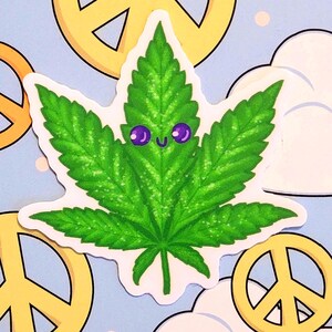 May include: A green cannabis leaf sticker with a smiling face and purple eyes. The sticker is on a light blue background with yellow peace signs and white cloud shapes.
