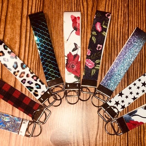 May include: Assortment of keychains with various patterns and designs, including floral, animal print, glitter, and stars. Each keychain features a silver metal ring.