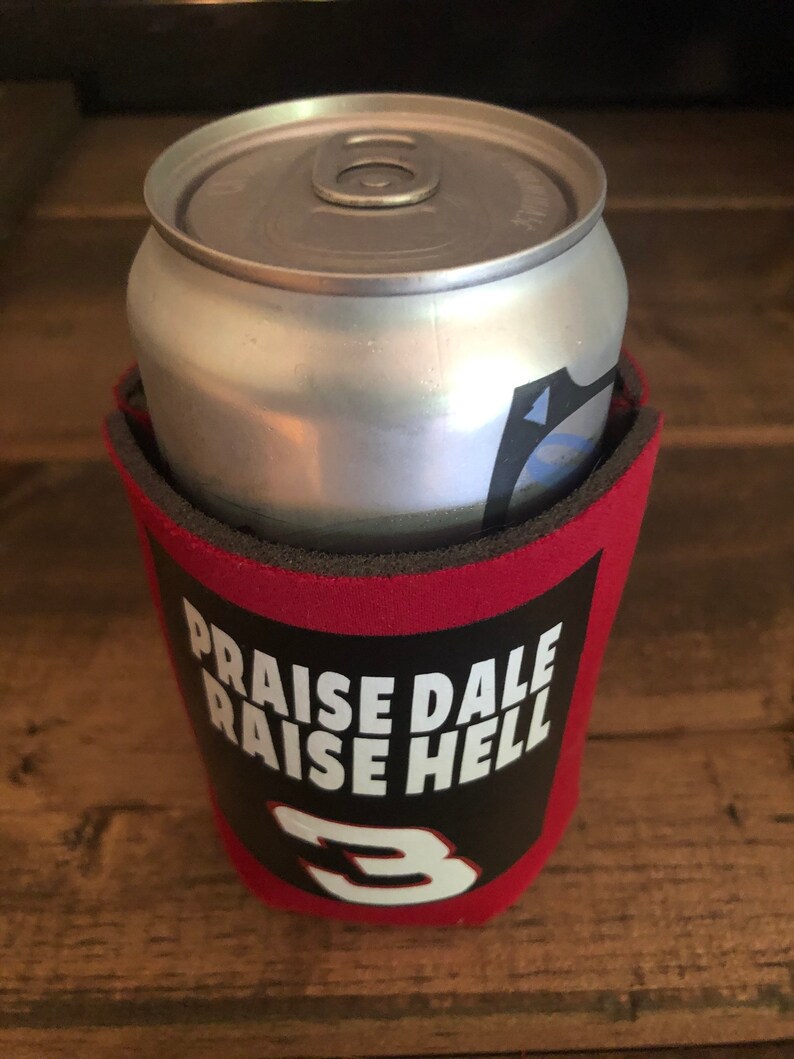 Puede incluir: Enfriador de latas rojo y negro con el texto "Praise Dale Raise Hell" y el n&uacute;mero "3" en blanco.