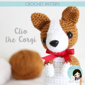 May include: Crochet pattern for a cute brown and white corgi dog amigurumi toy with a red bow. The pattern is called "Clio the Corgi".