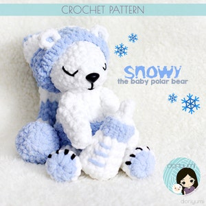 Op de afbeelding: Een gehaakte witte ijsbeer die een blauwe muts draagt en een blauw en wit flesje vasthoudt. De beer zit op een wit, pluche oppervlak. De tekst "Snowy the baby polar bear" is in zwarte letters op een witte achtergrond geschreven.