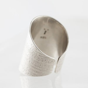 Peut inclure: Une bague en argent avec une surface textur&eacute;e et une ouverture fendue. La bague est marqu&eacute;e du num&eacute;ro "1" et du mot "925".
