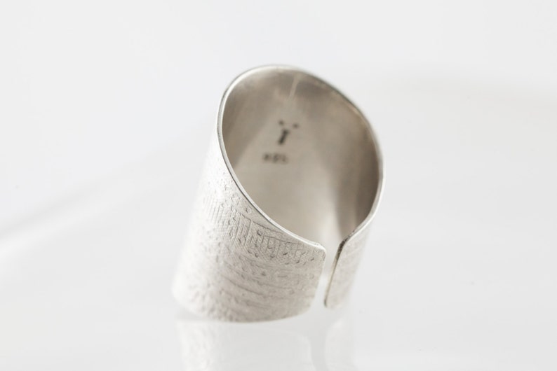 Peut inclure: Une bague en argent avec une surface textur&eacute;e et une ouverture fendue. La bague est marqu&eacute;e du num&eacute;ro "1" et du mot "925".