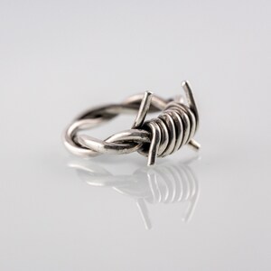 Può includere: Un anello d'argento a forma di filo spinato.