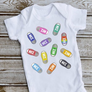 May include: White baby onesie with a colorful print of various sneakers. The sneakers are in different colors, including red, blue, green, yellow, and purple.