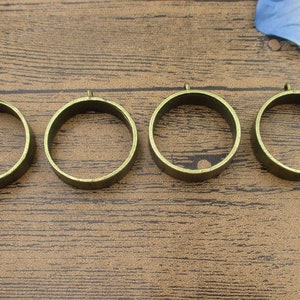 May include: Four round, gold-colored metal rings with a smooth finish. The rings are all the same size and are arranged in a row.
