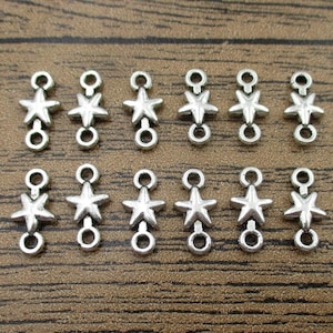 May include: Twelve silver-toned star-shaped connector charms with two jump rings each. The charms are arranged in two rows of six.