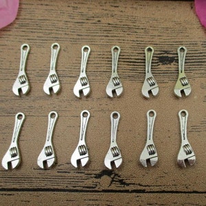 May include: Twelve silver-toned wrench charms, each with a detailed design. These charms are perfect for adding a touch of industrial style to jewelry or crafts.