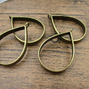 May include: Four antique gold-toned metal teardrop-shaped pendant blanks. The blanks have a smooth, polished finish and are ready to be filled with resin or other materials.