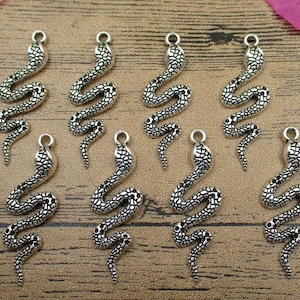 May include: Eight silver snake charms featuring detailed scales and a coiled body. The charms have a loop at the top for attaching to jewellery or other crafts.