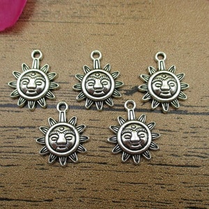 May include: Five silver charm pendants shaped like a sun with a face. Each pendant has a loop at the top for attaching to a chain or bracelet.