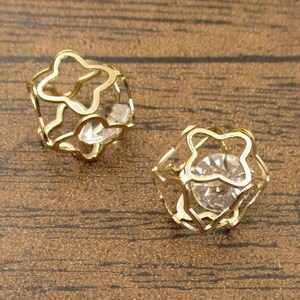 May include: A pair of gold-tone earrings with a clear crystal in the center of each earring. The earrings are shaped like a star.