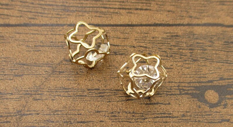 May include: A pair of gold-tone earrings with a clear crystal in the center of each earring. The earrings are shaped like a star.