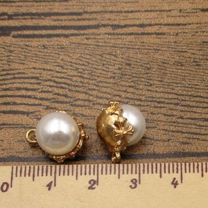 Puede incluir: Dos botones de n&aacute;car dorados con un dise&ntilde;o floral decorativo. Los botones miden aproximadamente 1 cm de di&aacute;metro y tienen un bucle en la parte posterior para coser.