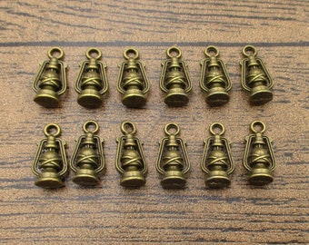 May include: A set of 12 antique gold-toned metal charms shaped like oil lamps. The charms have a detailed design and are perfect for adding a vintage touch to jewelry or crafts.
