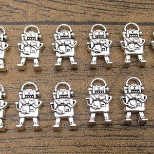 Puede incluir: Doce abalorios de robot plateados con un diseño de corazón. Los abalorios miden aproximadamente 2,5 cm de alto y tienen un bucle en la parte superior para sujetarlos a un collar o pulsera.