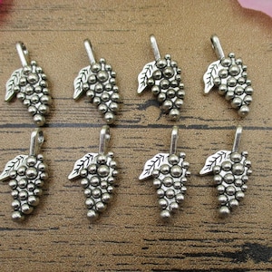 Puede incluir: Ocho colgantes de uva plateados con un detalle de hoja. Los colgantes miden aproximadamente 2,5 cm de largo.