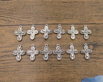 May include: A set of 12 silver-toned cross charms with intricate details. The charms are perfect for jewelry making, scrapbooking, and other craft projects.