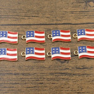 Puede incluir: Ocho abalorios de metal de color dorado con forma de banderas americanas. Cada abalorio tiene un bucle en la parte superior para sujetarlo a un collar, una pulsera u otra joya. Las banderas son rojas, blancas y azules con un diseño ondulado.