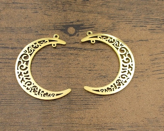 May include: Two gold-colored metal crescent moon charms with intricate cut-out designs. The charms have two small loops at the top for attaching to jewelry or other crafts.