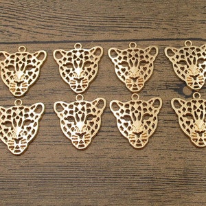 Puede incluir: Diez abalorios de metal de color dorado con forma de cara de leopardo. Los abalorios están detallados con un diseño estampado y tienen un agujero en la parte superior para sujetarlos a joyas u otras manualidades.