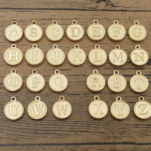 Um conjunto de amuletos de letras do alfabeto, dupla face banhada a esmalte champanhe-RS1213