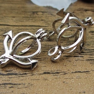 Könnte beinhalten: Zwei silberne Anhänger in Ankerform mit einem Käfigdesign. Die Anhänger sind offen und können verwendet werden, um kleine Gegenstände aufzubewahren.