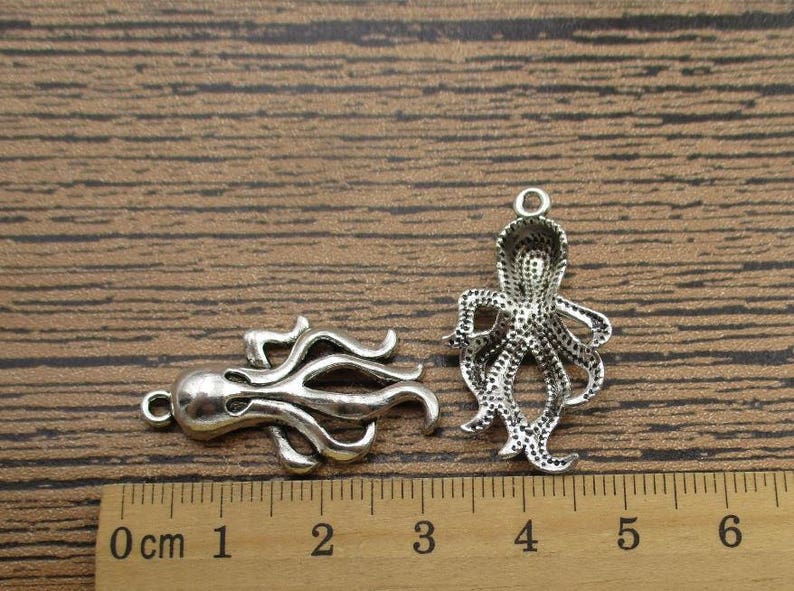 May include: Two silver octopus charms with detailed designs. The charms are approximately 2 cm in length and are perfect for jewelry making or crafting.