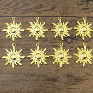 Peut inclure: Un ensemble de 14 breloques soleil en métal doré avec un centre surélevé. Les breloques sont parfaites pour la fabrication de bijoux ou l'artisanat.