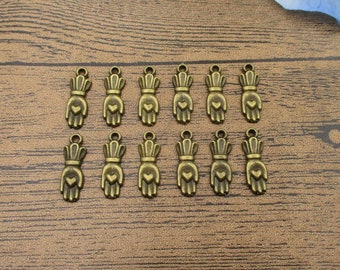 May include: A set of 12 antique gold-toned metal charms shaped like hands with a heart in the palm. The charms have a loop at the top for attaching to jewelry or other crafts.