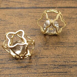 May include: A pair of gold-tone earrings with a clear crystal stone set in a cage-like design.
