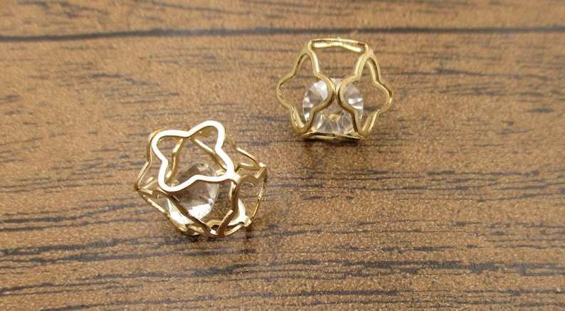 May include: A pair of gold-tone earrings with a clear crystal stone set in a cage-like design.