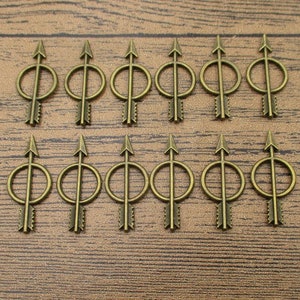 May include: A set of 12 antique gold arrow charms with a circle design. The charms are made of metal and have a rustic finish.