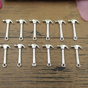 May include: Twelve silver-toned hammer charms, each with a loop for attaching to a necklace, bracelet, or other jewelry project.