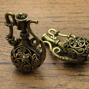 May include: Two ornate, gold-colored metal bottle stoppers shaped like a traditional Middle Eastern water pitcher with intricate floral designs.