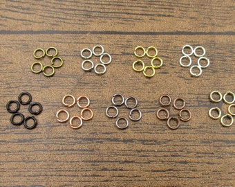 May include: Assortment of jump rings in various colors, including gold, silver, black, and copper. Each color is arranged in a circle with seven jump rings.