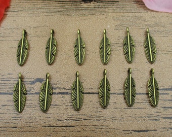 May include: A collection of 15 antique gold-toned metal feather charms. The charms are all the same size and shape, and they have a slightly textured surface.